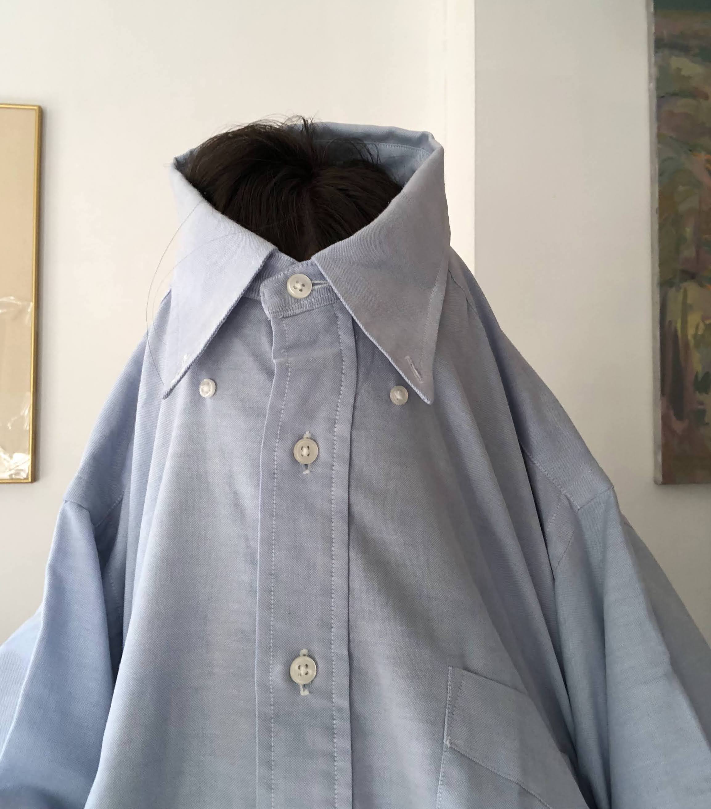 person wearing a blue button up shirt over their face
