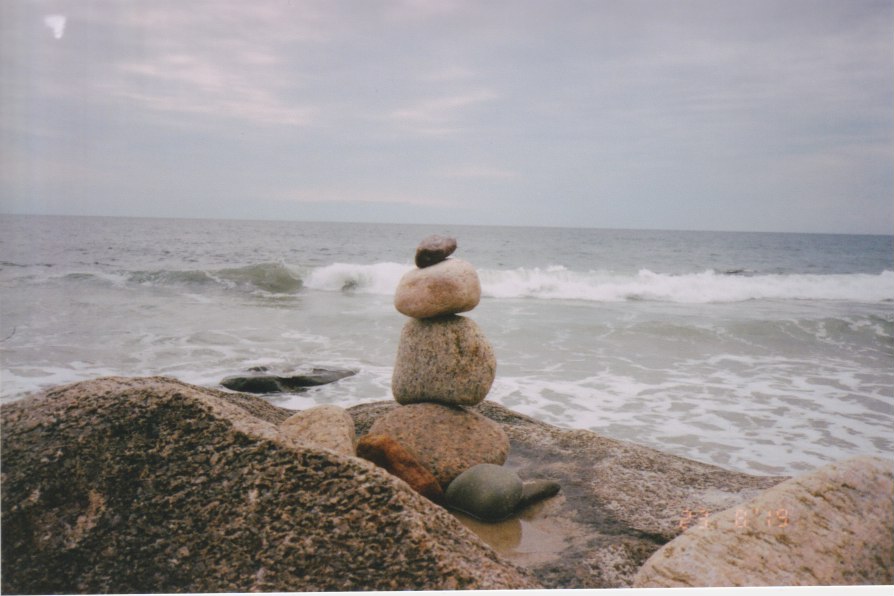 rock cairn in front of ocean waves and horizon