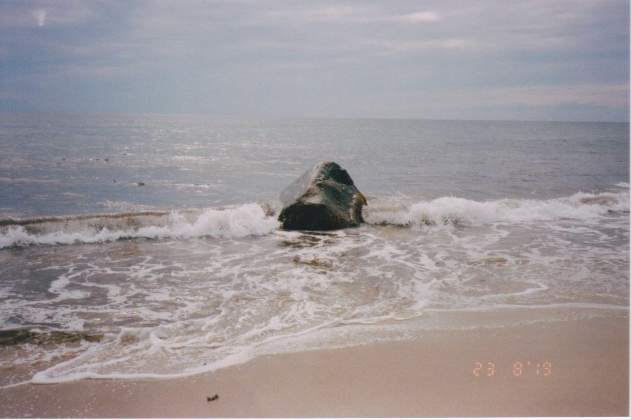 wave crashing on large rock on beach