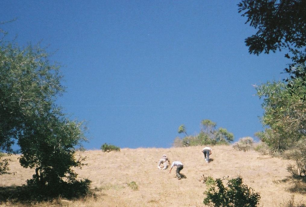three people climbing steep hillside