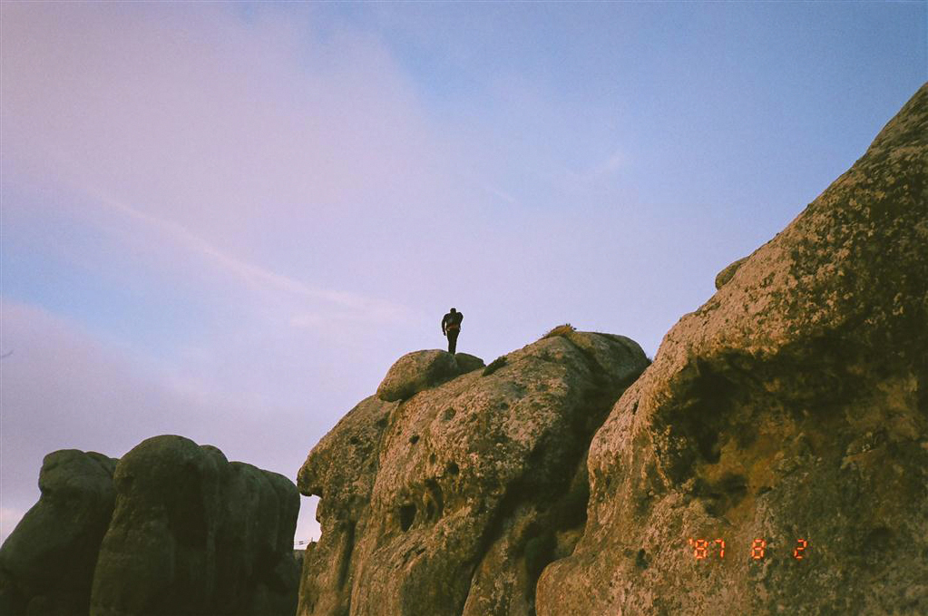 person standing at the top of a giant rock
