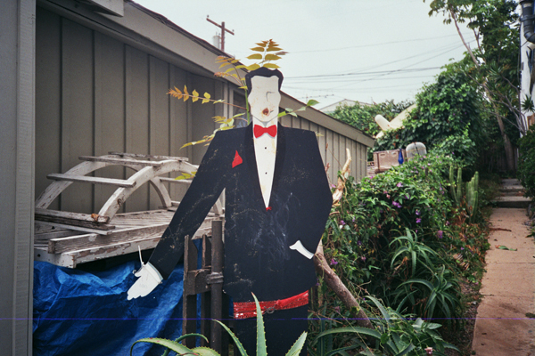 wooden cutout of a man in a tuxedo and red bowtie