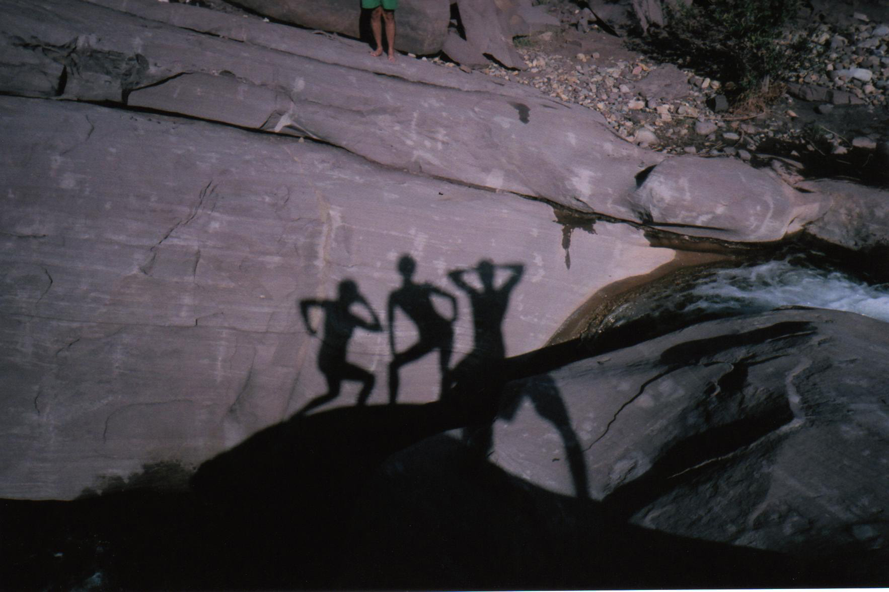 shadows of three figures striking poses on rocks