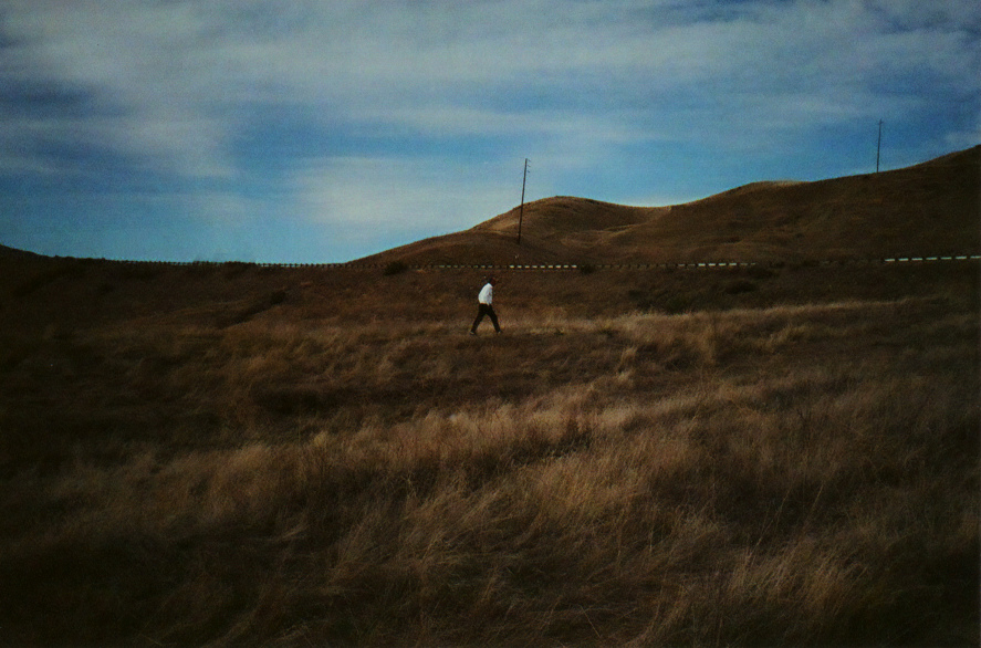 person in distance walking up a steep hill in empty landscape